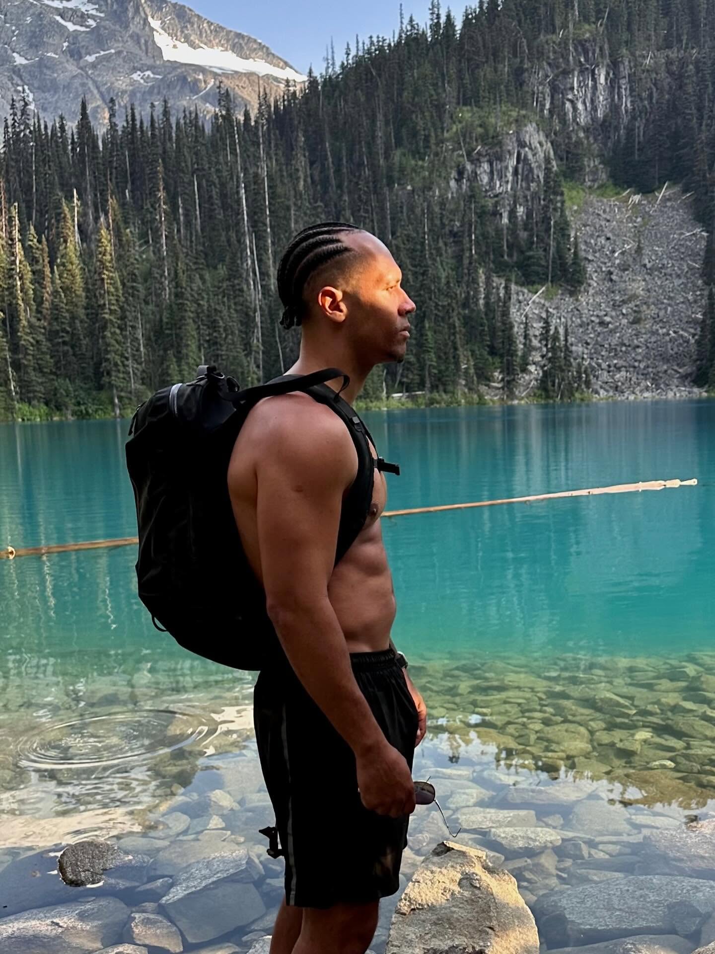 J.R. hiking beside a turquoise alpine lake in the mountains