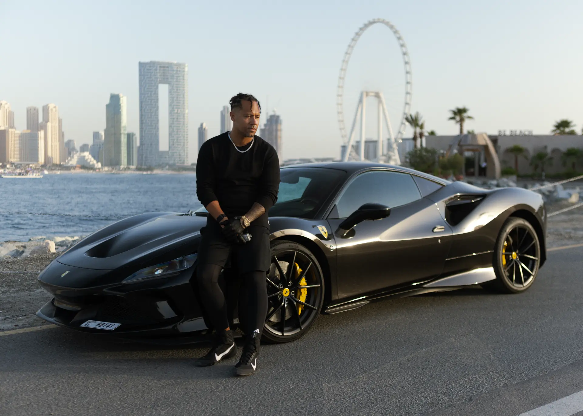 JR Lopez in Dubai standing beside a black Ferrari F8 with the Bluewaters skyline behind him